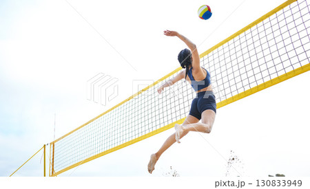 Sports, volleyball and woman jump at beach to hit ball in competition, game or match. Training, exercise and female athlete jumping for spike in tournament for workout, fitness and health at seashore Sports, volleyball and woman jump at beach to hit ball in competition, game or match. Training, exercise and female athlete jumping for spike in tournament for workout, fitness and health at seashore 130833949