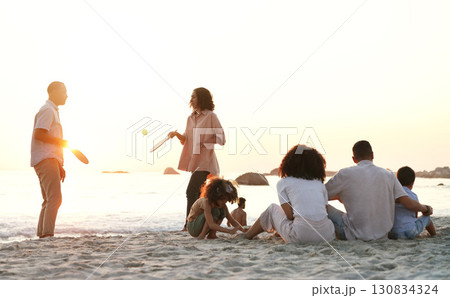Travel, game and family at the beach on a summer vacation, adventure or weekend trip in Australia. Sunset, fun and people playing sports on the sand by the ocean on seaside holiday together. 130834324