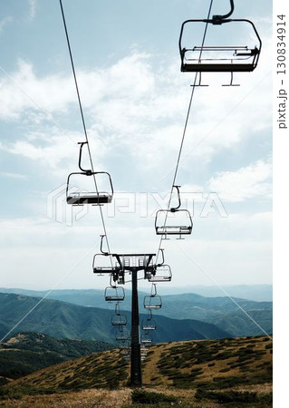 Empty chairlift rising above the green slopes of Stara Planina under a bright summer sky, with panoramic mountain views in the distance. Serbia country 130834914