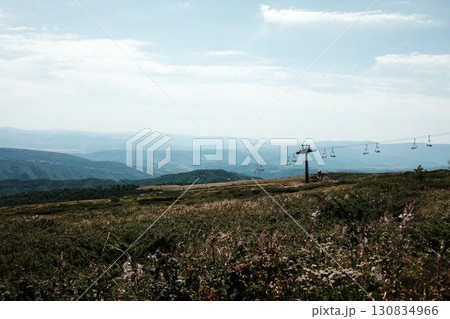 Mountain meadow with ski lift chairs stretching into the distance, surrounded by rolling hills and valleys of Stara Planina, Serbia country Mountain meadow with ski lift chairs stretching into the distance, surrounded by rolling hills and valleys of Stara Planina, Serbia country 130834966