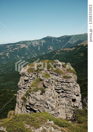 Rocky cliffs and green slopes of Stara Planina with mountain ridges in the distance. Babin Zub mount in summer season. Serbia country Rocky cliffs and green slopes of Stara Planina with mountain ridges in the distance. Babin Zub mount in summer season. Serbia country 130835003