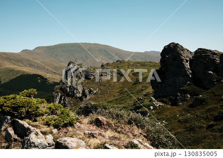 Rocky cliffs and green slopes of Stara Planina with mountain ridges in the distance. Babin Zub mount in summer season. Serbia country 130835005