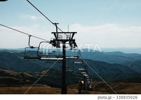 Ski lift chairs on Stara Planina mountain with panoramic view of green hills and valleys. Serbia country in summer season Ski lift chairs on Stara Planina mountain with panoramic view of green hills and valleys. Serbia country in summer season 130835026
