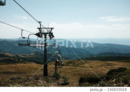 Ski lift chairs on Stara Planina mountain with panoramic view of green hills and valleys. Serbia country in summer season Ski lift chairs on Stara Planina mountain with panoramic view of green hills and valleys. Serbia country in summer season 130835028