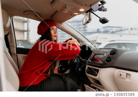 Woman, driving, car. Stylish female driver thoughtfully looking out from modern vehicle. 130835389