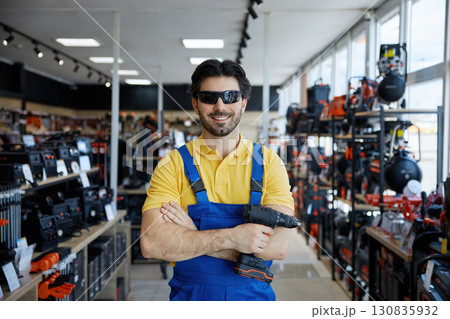 A man worker in stylish sunglasses, is holding a drill in a store 130835932