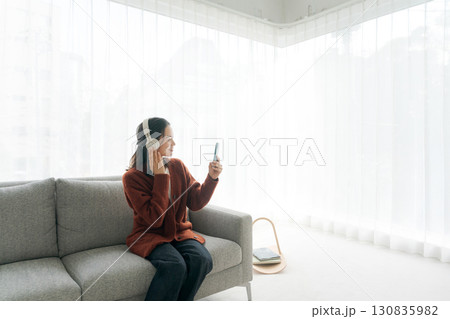 ソファに座って音楽を聴く女性 130835982