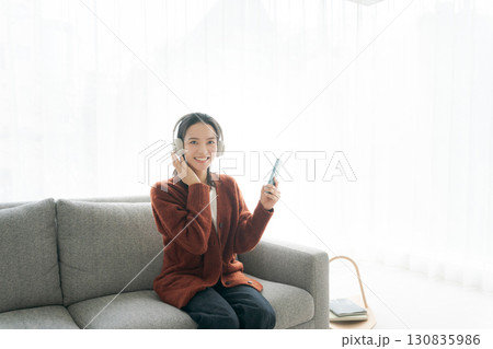 ソファに座って音楽を聴く女性 130835986