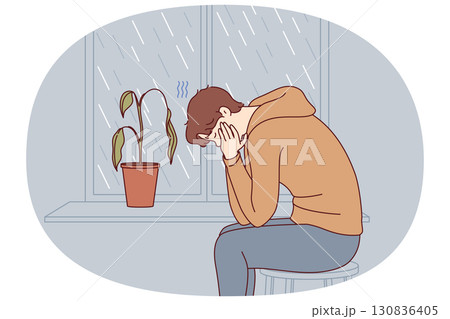 Depressed man sits alone and suffers from melancholy in room with window and wilted flower Depressed man sits alone and suffers from melancholy in room with window and wilted flower 130836405
