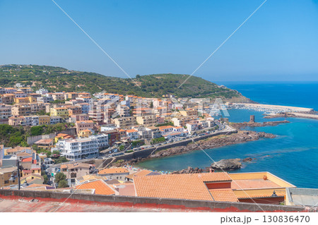 Charming Mediterranean townscape with colorful houses overlooking a serene harbor. Capturing the essence of coastal living, the scene is framed by verdant hills and azure waters. 130836470