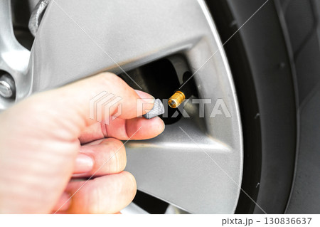 Hand opening tire valve cap on car wheel rim, vehicle air valve for checking tire pressure 130836637