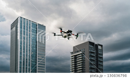 Drone Flying Amidst Tall Buildings Under Cloudy Sky in an Urban Environment 130836798