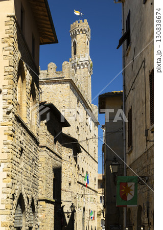 Palazzo dei Priori rising over narrow street in Volterra, Tuscany 130838674