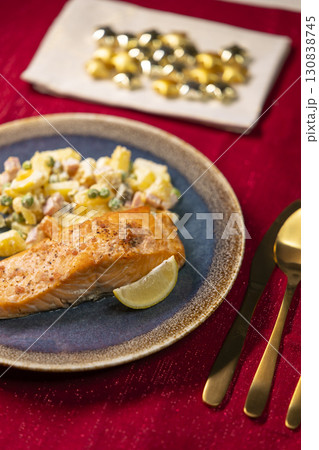 Grilled salmon fillet with russian salad and lemon slice on christmas table setting 130838745
