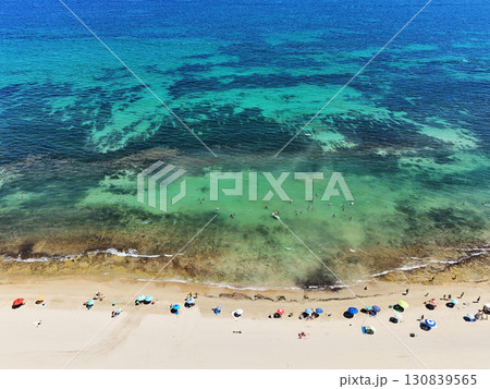 Colorful beach umbrellas and swimmers in turquoise sea Colorful beach umbrellas and swimmers in turquoise sea 130839565