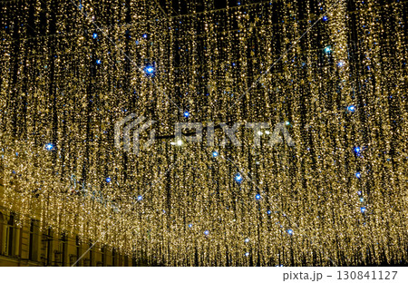 A mesmerizing night shot of a street or public square ceiling, covered by thousands of shimmering golden and blue fairy lights 130841127