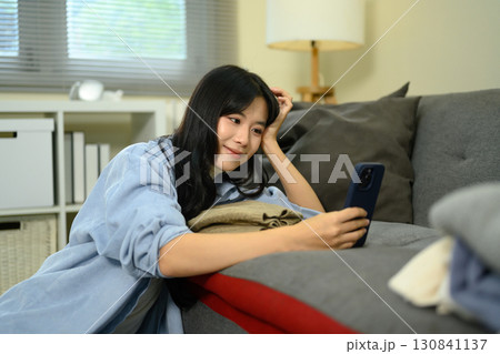 Female traveler checking phone messages while packing clothes for a trip at home Female traveler checking phone messages while packing clothes for a trip at home 130841137