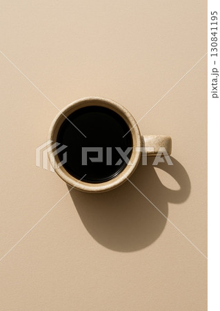 Top view of black coffee in ceramic cup on vertical beige background. Minimalist coffee break concept, copy space. 130841195