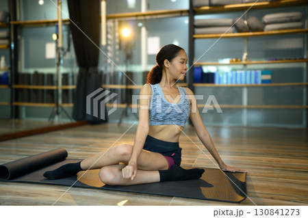 Female athlete stretching and twisting body during yoga session Female athlete stretching and twisting body during yoga session 130841273