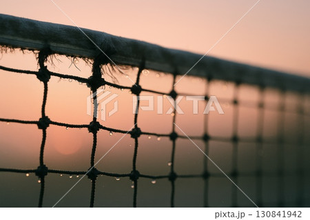 Close-up shot of a net with water droplets against a soft sunset background. Close-up shot of a net with water droplets against a soft sunset background. 130841942