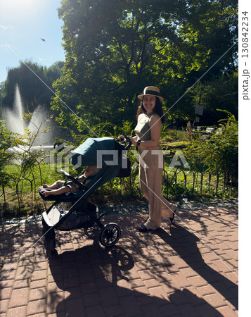 Woman Strolling with Child in Park on Sunny Day Woman Strolling with Child in Park on Sunny Day 130842234