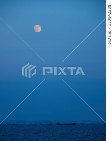 夏の夕方の東京湾の海面と空の月と貨物船の風景 130842288