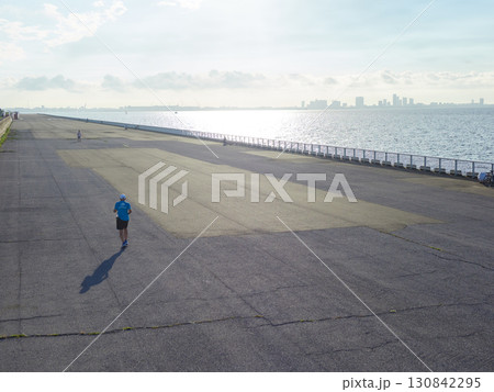 夏の新浦安総合公園の海岸の堤防でランニングする男性の姿 130842295