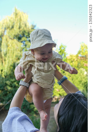 Joyful Baby Lifted in the Air Outdoors 130842323