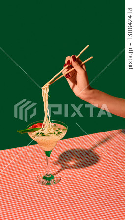 Hand with chopsticks lifting noodles from martini glass with tomato and onion garnish Hand with chopsticks lifting noodles from martini glass with tomato and onion garnish 130842418
