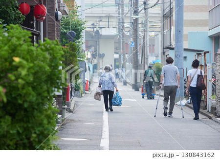 夏の朝の都市の商店街で歩くシニア女性と人々の姿 夏の朝の都市の商店街で歩くシニア女性と人々の姿 130843162