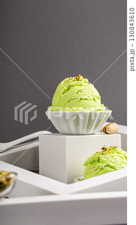 Green pistachio ice cream scoop in a decorative bowl on a minimalist white display Green pistachio ice cream scoop in a decorative bowl on a minimalist white display 130843610
