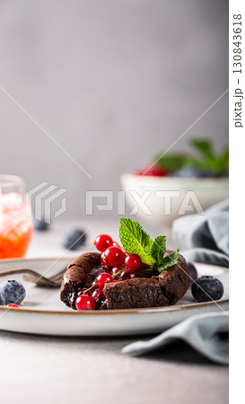 Decadent chocolate dessert topped with fresh berries and mint leaves on a stylish plate 130843618