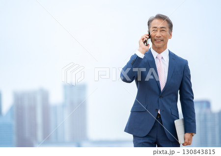 ビジネスマン　ビル群　スマホ 130843815