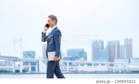 ビジネスマン　ビル群　スマホ 130843823