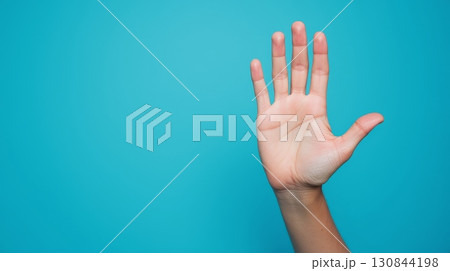 Hand showing five fingers with bright blue background with copy space. 130844198