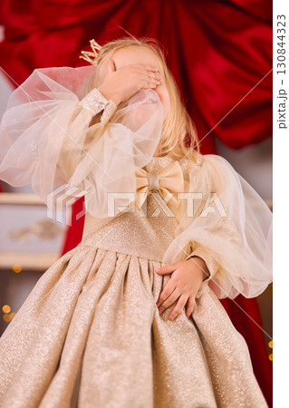 Shy Little Girl in a Gold Festive Dress 130844323