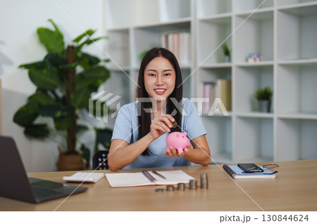 Empowered Saving: Woman with Piggy Bank and Coins Empowered Saving: Woman with Piggy Bank and Coins 130844624