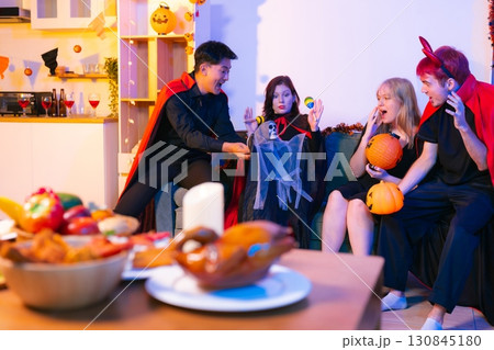 Dinner and group of people celebrating together at Halloween party. 130845180