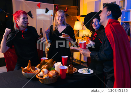 Dinner and group of people celebrating together at Halloween party. 130845186