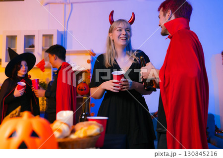 Dinner and group of people celebrating together at Halloween party. 130845216
