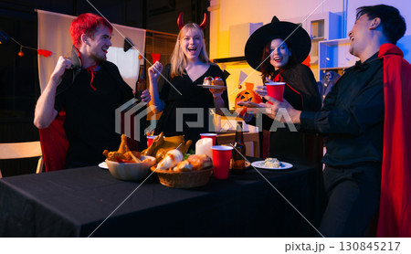 Dinner and group of people celebrating together at Halloween party. 130845217