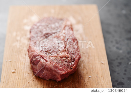 Raw ribeye steak spiced and ready to cook on oak board 130846034