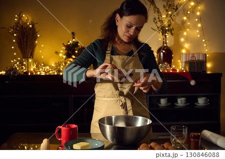 Woman Baking Cookies in a Festive Kitchen with Christmas Lights 130846088