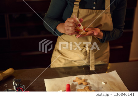 Woman Decorating Gingerbread Cookies for Christmas Preparing Festive Homemade Treats 130846141