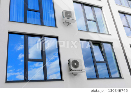 Condenser unit or compressor outside of residential building. Unit of central air conditioner AC or heating ventilation air conditioning system HVAC. Electric fan AC hangs on the wall Condenser unit or compressor outside of residential building. Unit of central air conditioner AC or heating ventilation air conditioning system HVAC. Electric fan AC hangs on the wall 130846746