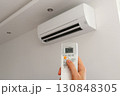 Air conditioner temperature adjustment with remote controller in room at home. Hand holding remote controller of air conditioner inside the white room and set at cool temperature 130848305