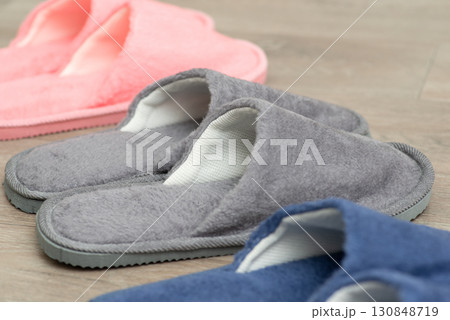 Three pairs of slippers on the floor. Colourful home footwear on the floor Three pairs of slippers on the floor. Colourful home footwear on the floor 130848719