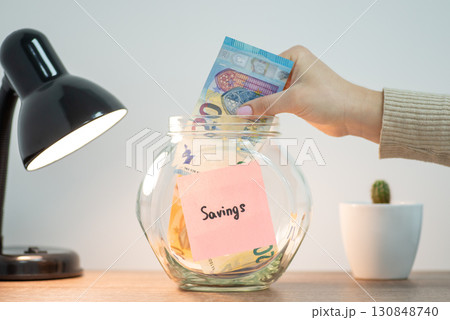 Putting euro banknote into glass jar. Savings concept, collecting money for a big purchase 130848740