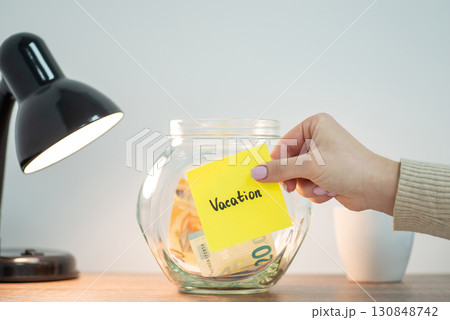 Female hand sticking paper with inscription Vacation to the bank with some euro money. Savings for vacation in Europe concept 130848742
