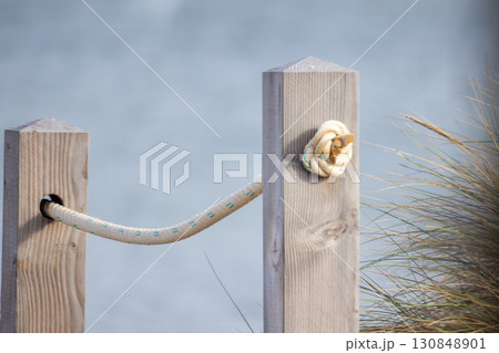 Artistic Coastal Post Featuring Rope and Shell Detail Captured Beautifully by the Shoreline Artistic Coastal Post Featuring Rope and Shell Detail Captured Beautifully by the Shoreline 130848901